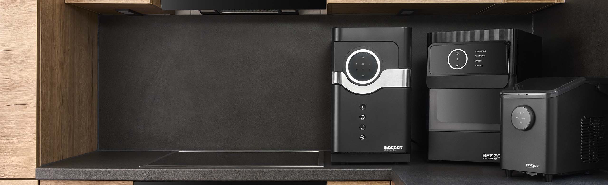 3 black BEEZER appliances on the worktop in a dark kitchen