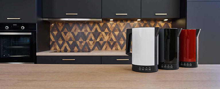 A picture of a red, a black and a white kettle standing next to each other on a kitchen platform.