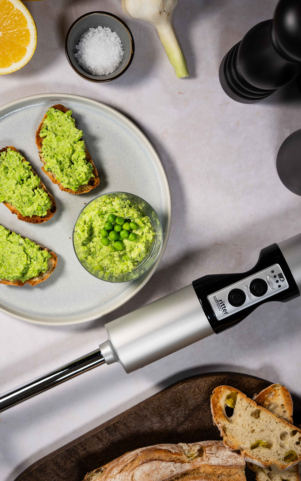Grüner Erbsen-Minz-Dip mit frischen Erbsen und geröstete Brotscheiben mit Erbsenaufstrich, angerichtet auf einem Teller.