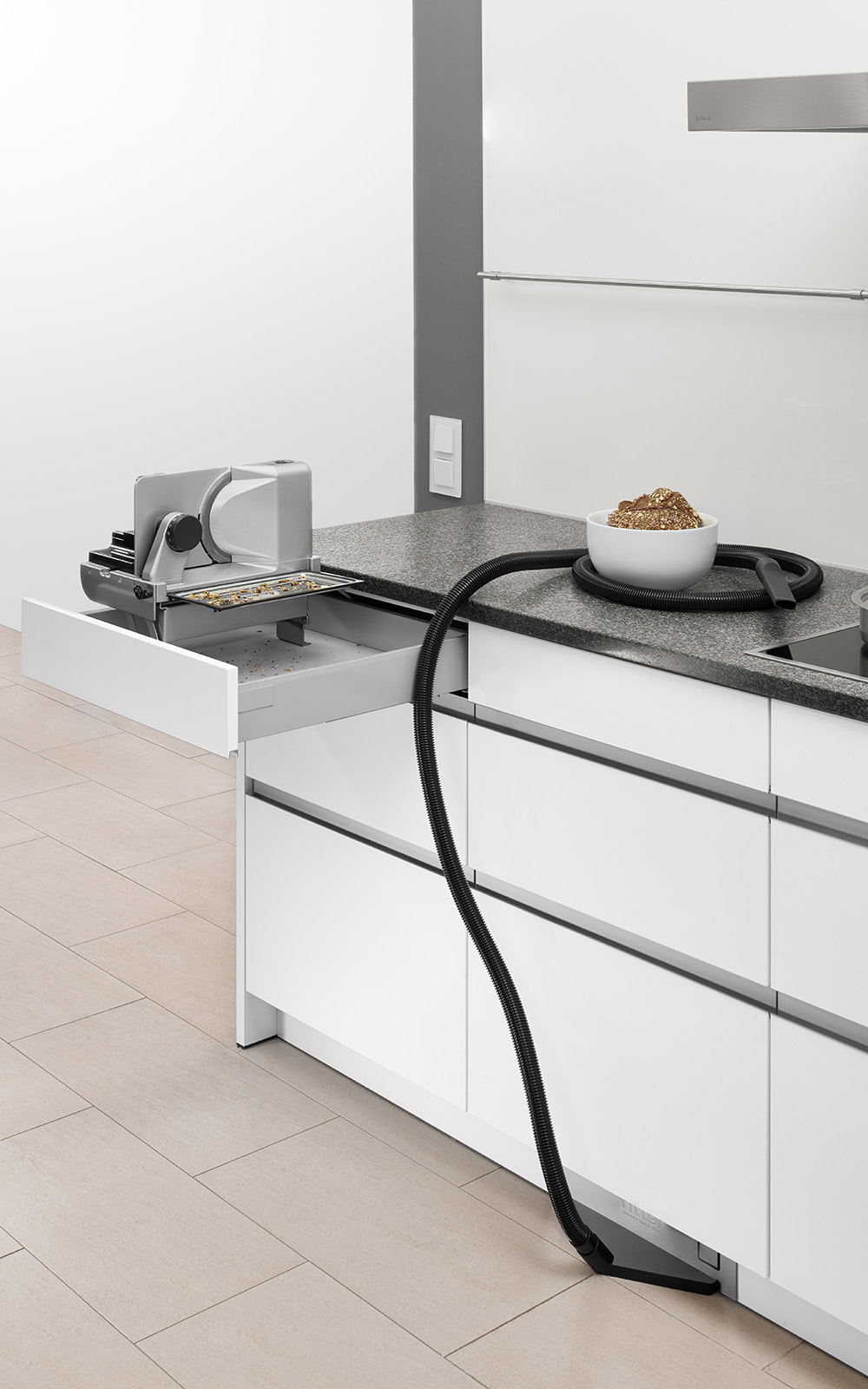 A picture of a built-in combination in a kitchen consisting of a built-in pedestal vacuum cleaner and a left-guided and upright built-in all-purpose slicer. A picture of a built-in combination in a kitchen consisting of a built-in pedestal vacuum cleaner and a left-guided and upright built-in all-purpose slicer.