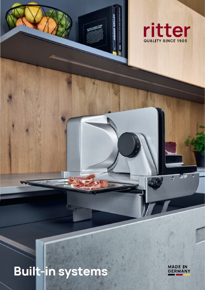A picture from the cover of an English catalog showing a built-in all-purpose slicer slicing a ham and emerging from a kitchen drawer.