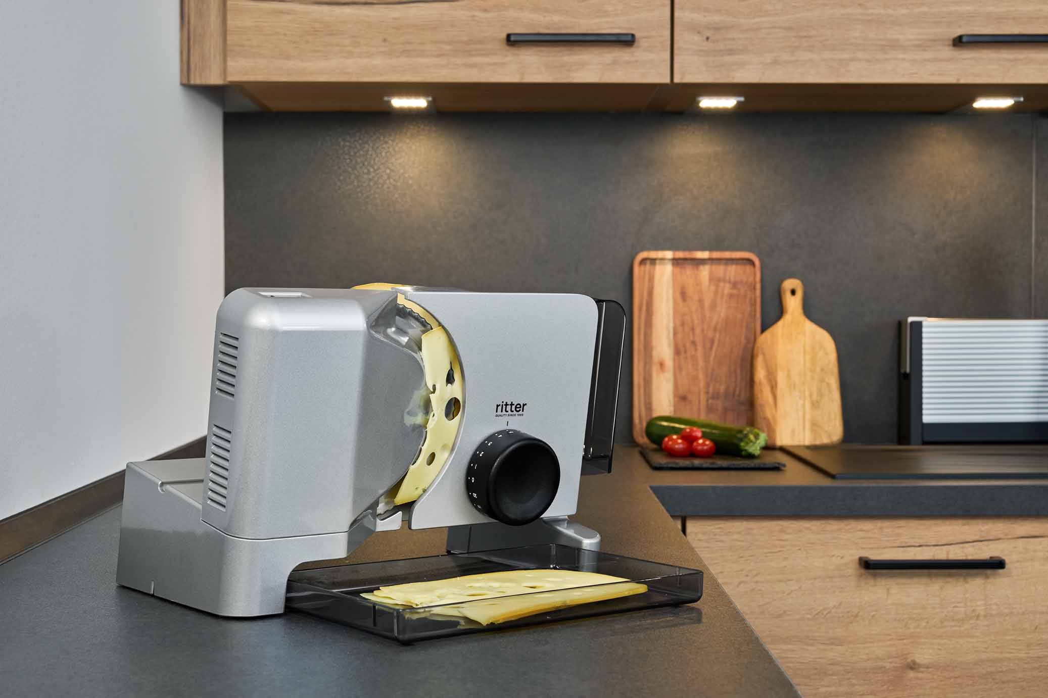 Electric food slicer with sliced cheese, in a modern kitchen