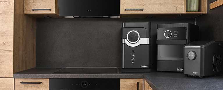 3 black BEEZER appliances on the worktop in a dark kitchen