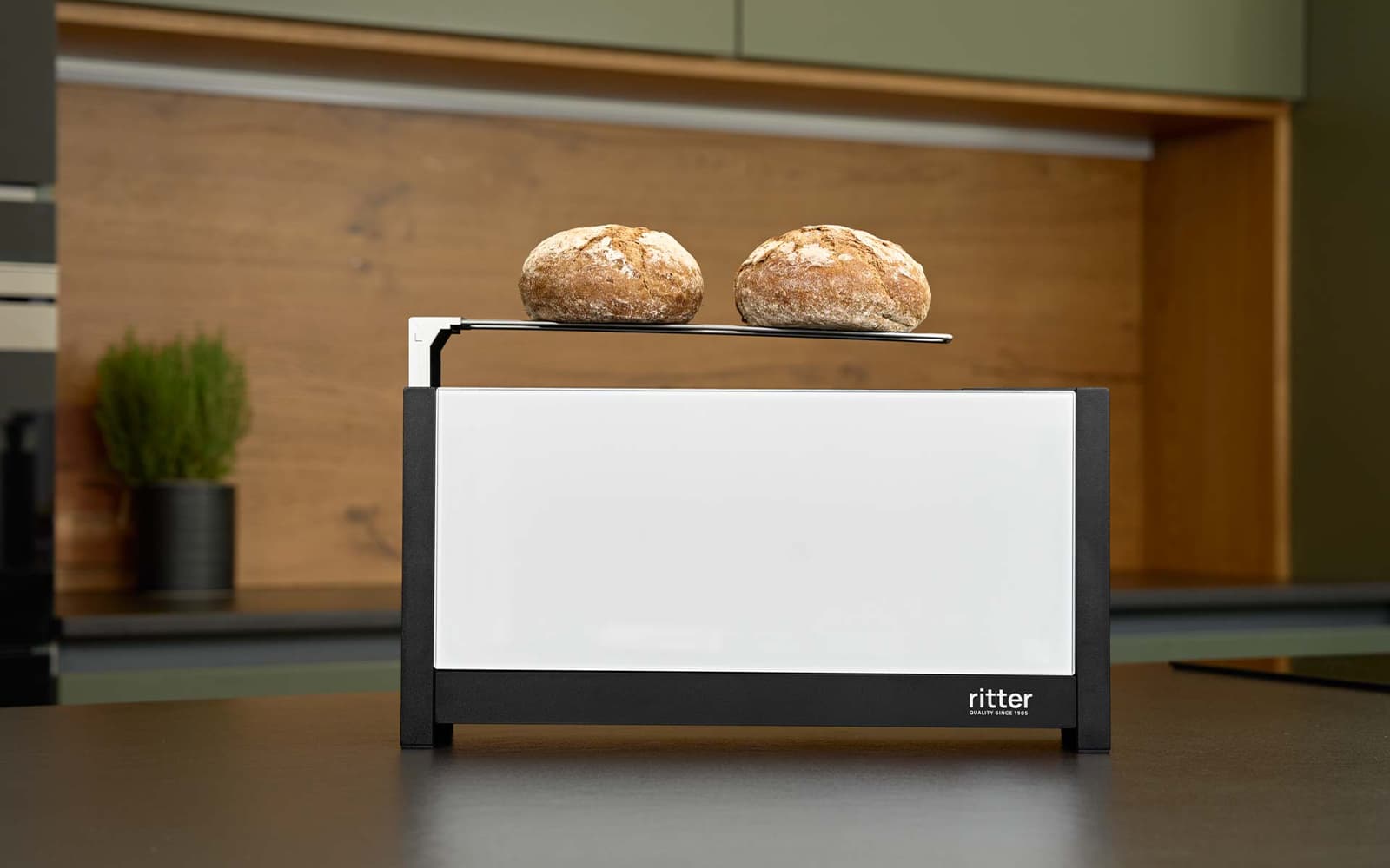 A picture of a white toaster with bread on the bread roll tray and standing on a kitchen platform.